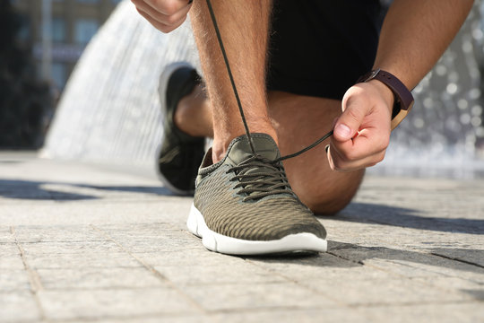 Sporty man tying shoelaces before running outdoors