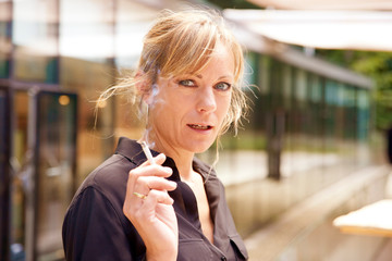 Middle aged woman smoking cigarette while standing outdoor