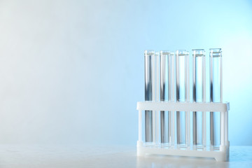 Test tubes with liquid samples on table against toned blue background, space for text. Laboratory analysis