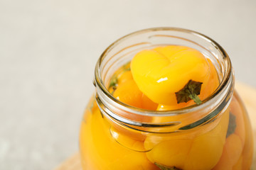 Glass jar with pickled peppers on grey table, closeup