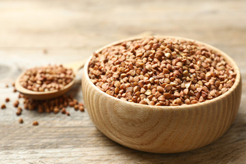 Bowl of uncooked buckwheat on wooden table