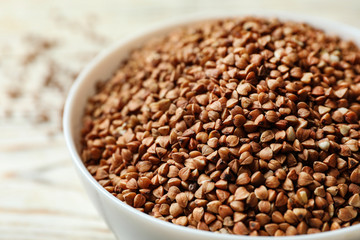 Bowl of uncooked buckwheat on table, closeup