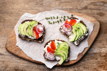 Delicious avocado sandwiches on wooden table, top view
