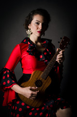 Fototapeta premium Carmen beautiful woman in red dress, with guitar on dark background