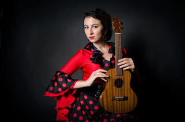 Obraz premium Carmen beautiful woman in red dress, with guitar on dark background