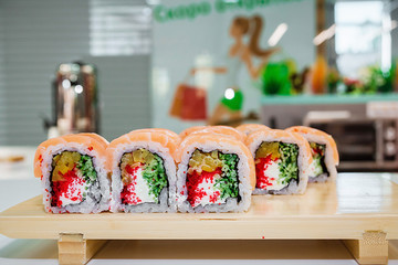 Big rolls laid out on the board. Sushi in three rows