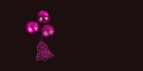 Pink New Year's toys on dark background. Christmas balls and bell. Merry Christmas and Happy New Year decoration concept