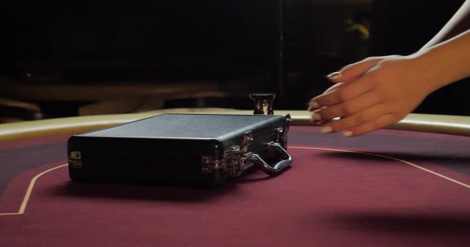 Poker table with poker chips in suitcase and falling on the table in casino. Poker chips for gambling card game.