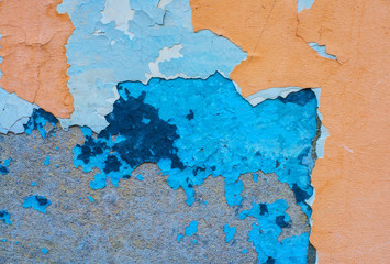 Concrete wall covered with several layers of peeling paint.