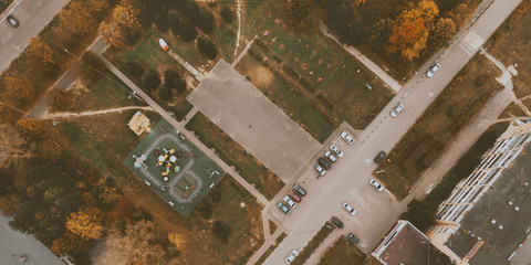 Courtyard of small town with children playground, parking with cars, green lawn and roads. Drone view. Banner background