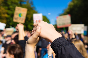 two young people at a rally, joining hands together signaling peace, unity and decisiveness in...