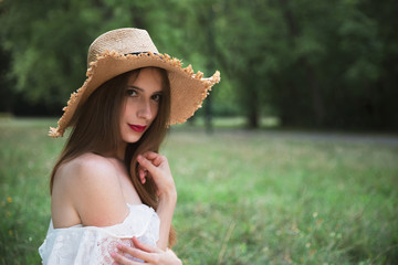 Young attractive girl in a straw hat and with long hair.