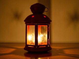 Advent lantern on the background of a warmly lit wall.
