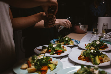 Man chef prepares the dish. Male hands sprinkle the salad with spices. Frendly kitchen and salad dressing.