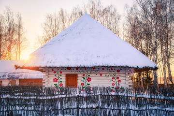 Traditional ancient Russian hut with straw roof covered with snow. Cold winter weather and sunset. - 300728570