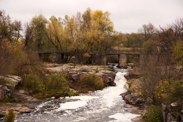 Foto op Canvas A stormy river flows under a bridge. Foamy river, rocks and bridge. Autumn colors © Kozachenko Oleksandr