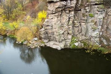 Deurstickers View of the high cliffs of the canyon. River and rocks. Autumn leaves fall in the river © Kozachenko Oleksandr