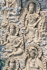 Da Nang, Vietnam - March 10, 2019: Chua An Long Chinese Buddhist Temple. Gray stone happy  multiple different Bodhisattvas fresco as backdrop for Guan Yin statue, not in picture.