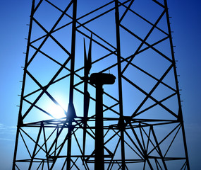 Silhouettes of wind turbine and electric tower with blue sky background at sunrise