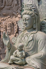 Da Nang, Vietnam - March 10, 2019: Chua An Long Chinese Buddhist Temple. Closeup of greenish marble statue of Guam Yin bust with child on lap.