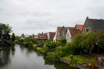 Fototapeta na wymiar View of traditional houses, trees, plants and canal in Edam. It is a town famous for its semi hard cheese in the northwest Netherlands, in the province of North Holland.
