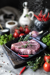 Raw fresh meat. Steak for two with ingredients in a grill pan, with spices, vegetables and herbs