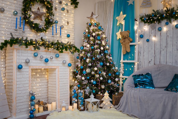 Christmas and New Year living room interior with decorated firtree, fireplace, blue candles, garland lights, brown teddy bear toy
