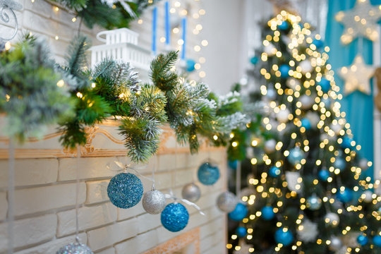 Christmas And New Year Living Room Interior With Decorated Firtree, Fireplace, Blue Candles, Garland Lights