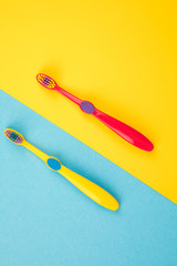 Teeth brushing concept. Toothbrushes on a yellow and blue background top view