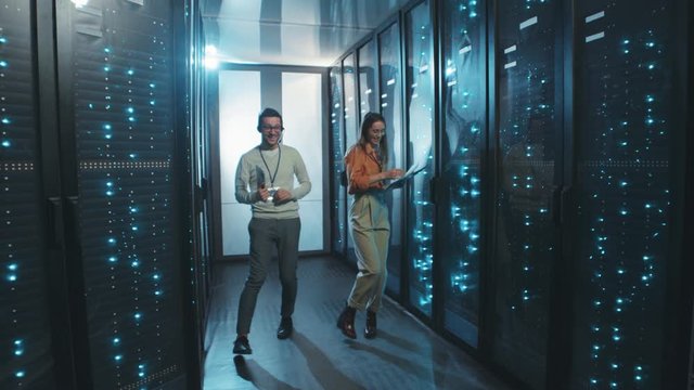 In data center couple of IT server workers having good time dancing relaxing on break in server rack corridor. Fun at work.