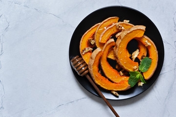 Baked sweet pumpkin with honey and rosemary on a gray concrete background. View from above.