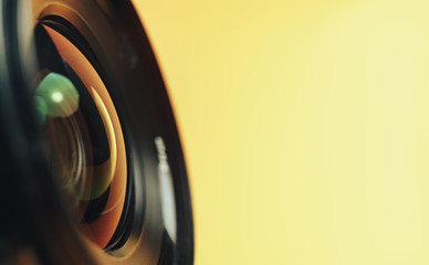 Beautiful camera lens with yellow and pink light of glass on a black background...