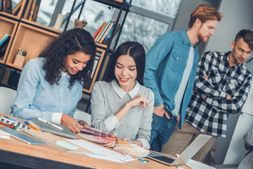 Startupers working together at office female designers sitting at table choosing color from palette happy