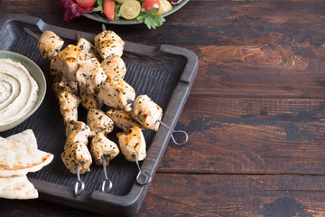 Grilled chicken skewers with hummus and salad