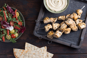 Grilled chicken skewers with hummus and salad