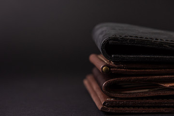 leather wallets on a black background with space for an inscription. Leather craft concept. - obrazy, fototapety, plakaty