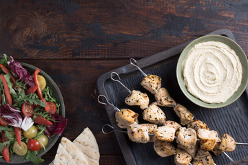Grilled chicken skewers with hummus and salad