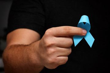 Men's hands hold a blue ribbon. November month health check. Prevention of prostatitis. Cancer Awareness. No Shave Month.