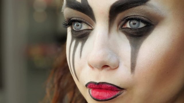 Easy Halloween Makeup. Applying makeup to the face. Applying red paint on the lips. The face of a crying girl.