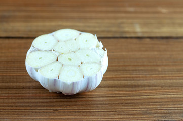 garlic head with slice on wooden background