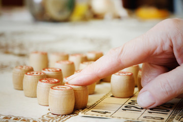 People playing lotto game in nursing home. Closeup of old people's fingers. Board game lotto or bingo. Wooden lotto barrels with numbers lying on lotto cards.