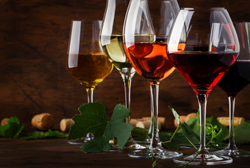 Wine set. Red, white and rose wine in assortment in wineglasses. Wine tasting, vintage wooden...