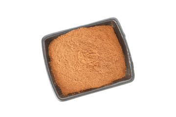 Black sauceboat with cinnamon powder isolated on white background