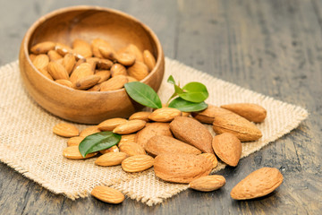 Some almonds, peeled and unpeeled nuts in the wooden bowl on the table.