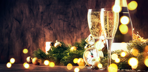 Two champagne glasses and christmas decoration on wooden snow golden bokeh background. Happy New...