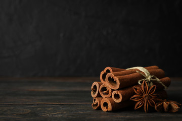 Cinnamon sticks and anise stars on wooden background, space for text