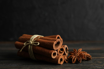 Cinnamon sticks and anise stars on wooden background, space for text