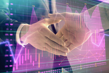 Multi exposure of forex graph on abstract background with two businessmen handshake. Concept of success on stock market