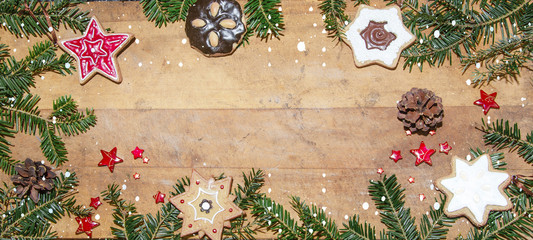 Frame of cookies and pine branches on rustic wooden table - christmas background panorama banner long - top view