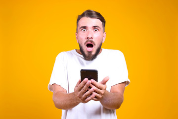 Young handsome man with facial hair posing yellow gray wall with a lot of copy space for text. Portrait of confident bearded male, wearing blank white oversized t-shirt. Isolated, background.